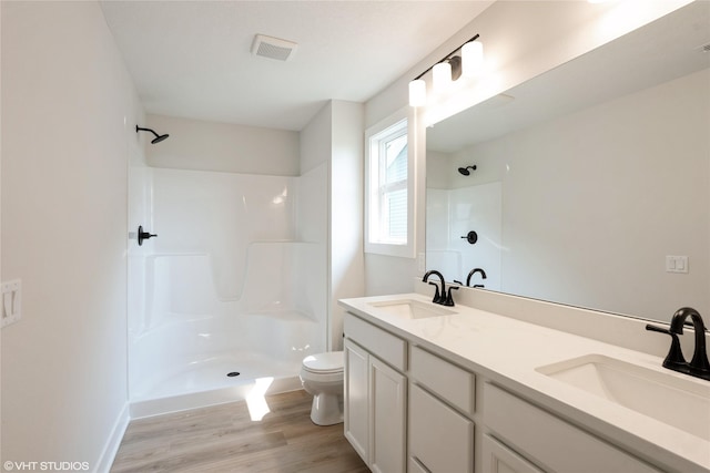 2908 Yordi Dr, Norwalk, IA 50211 - bathroom with toilet, a shower, wood finished floors, double vanity, and baseboards