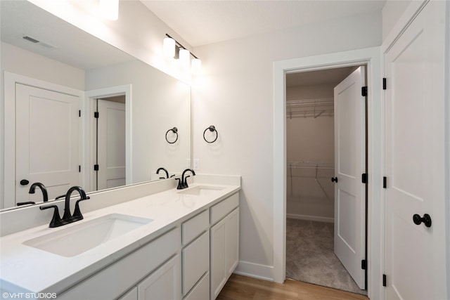 2908 Yordi Dr, Norwalk, IA 50211 - bathroom with double vanity, wood finished floors, a spacious closet, and baseboards