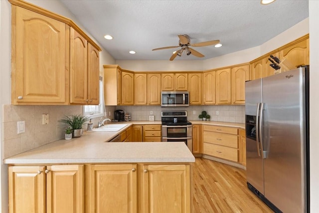 kitchen featuring stainless steel appliances, light countertops, light brown cabinets, ceiling fan, and a peninsula