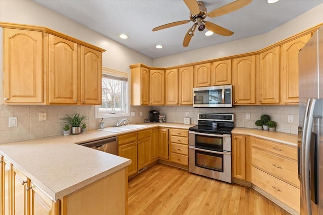 kitchen featuring light brown cabinetry, light countertops, appliances with stainless steel finishes, and light wood-style flooring