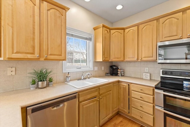 kitchen featuring backsplash, light brown cabinets, stainless steel appliances, and a sink