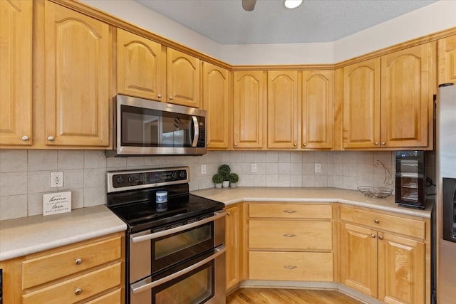 kitchen featuring stainless steel appliances, light countertops, light wood-style floors, and backsplash