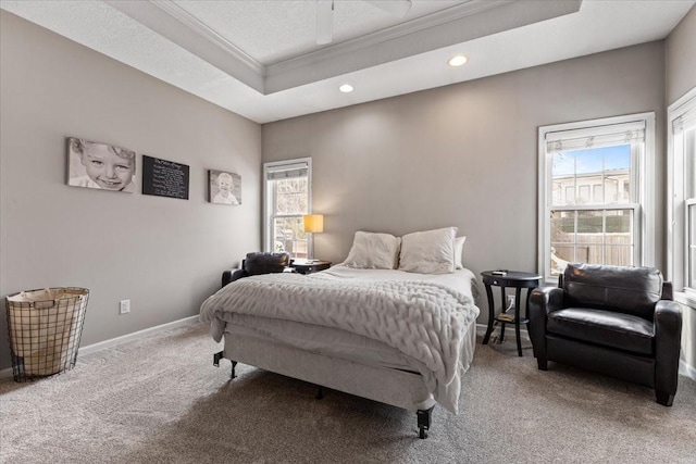 carpeted bedroom featuring ornamental molding, a tray ceiling, multiple windows, and baseboards