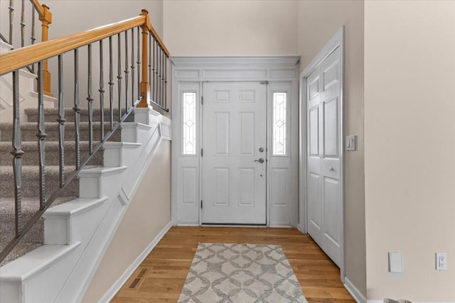 foyer entrance with visible vents, baseboards, and wood finished floors