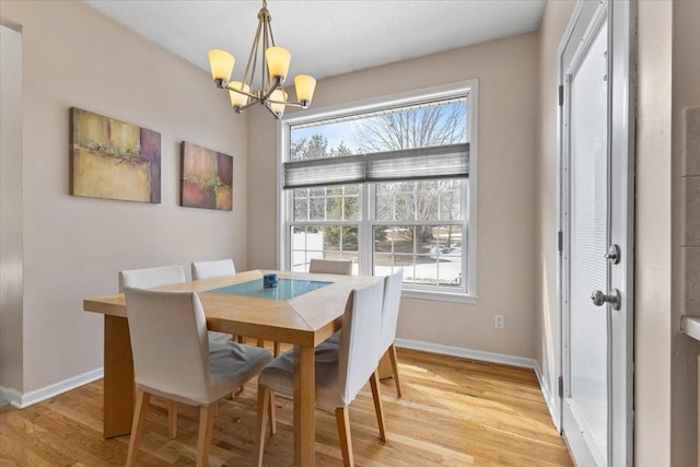 dining space featuring a chandelier, baseboards, plenty of natural light, and light wood finished floors