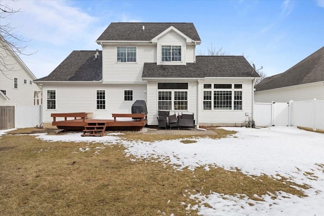 snow covered property with a fenced backyard, a gate, roof with shingles, and a wooden deck