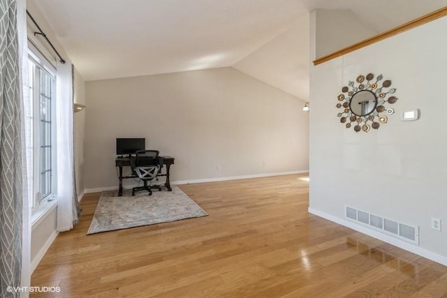 office area with lofted ceiling, light wood-style floors, baseboards, and visible vents