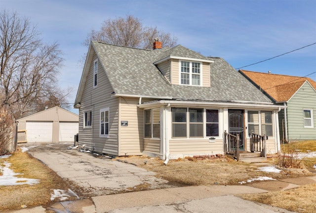 view of front of house featuring an outbuilding, a shingled roof, a chimney, and a detached garage