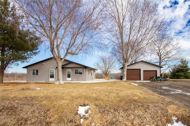 view of property exterior featuring an outbuilding, a patio area, a lawn, and a detached garage