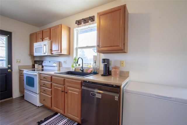 kitchen featuring white appliances, light wood-style floors, light countertops, and a sink