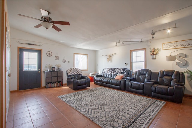 tiled living area with a ceiling fan, vaulted ceiling, rail lighting, and plenty of natural light