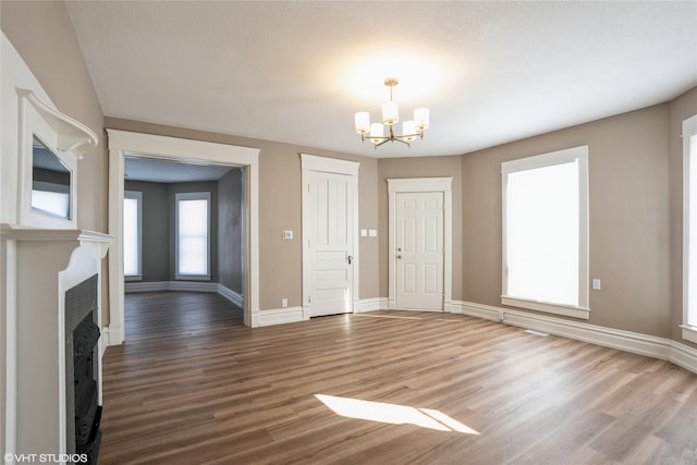 foyer featuring a chandelier, a fireplace with flush hearth, wood finished floors, and baseboards