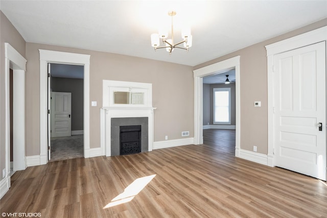 unfurnished living room featuring baseboards, light wood-type flooring, a fireplace, and a notable chandelier