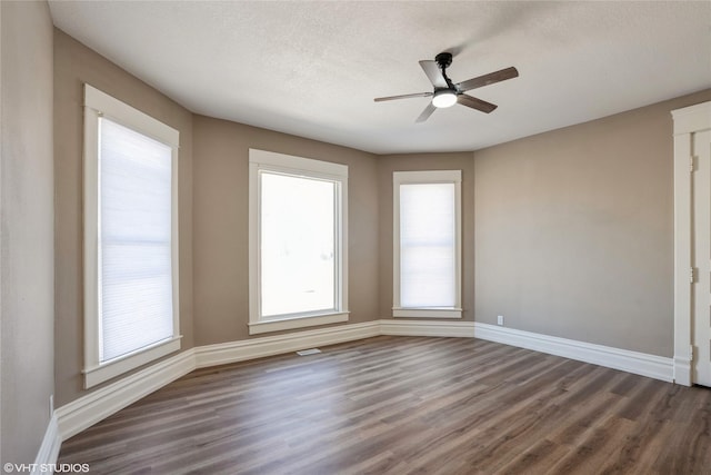 empty room featuring a textured ceiling, ceiling fan, wood finished floors, and baseboards