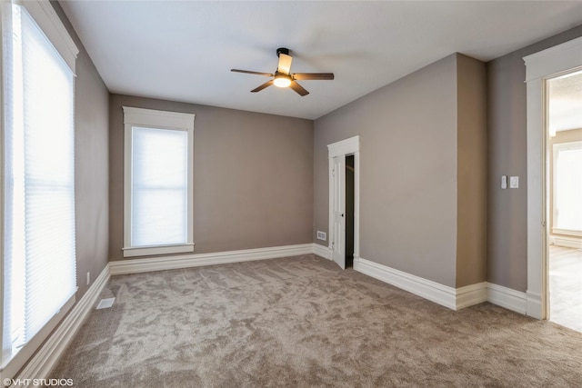 carpeted empty room with ceiling fan and baseboards