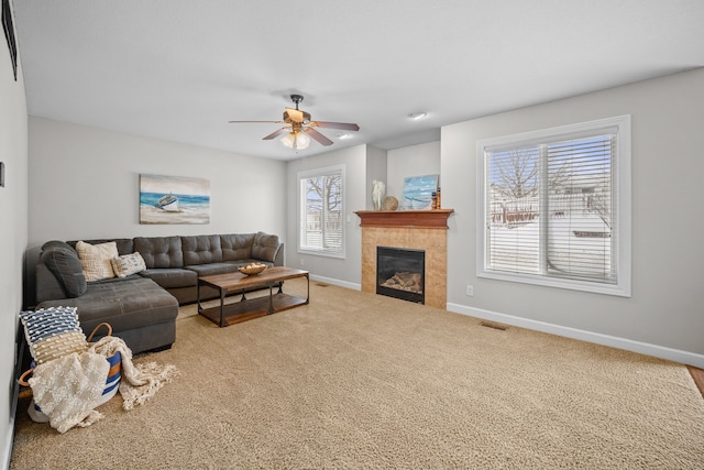 carpeted living room featuring visible vents, a tiled fireplace, baseboards, and ceiling fan