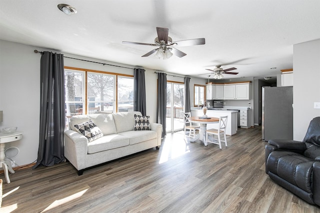 living area with a ceiling fan and wood finished floors