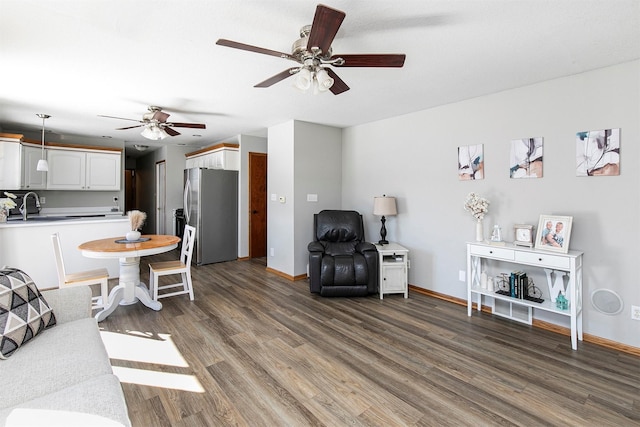 living area featuring dark wood-style flooring, a ceiling fan, and baseboards