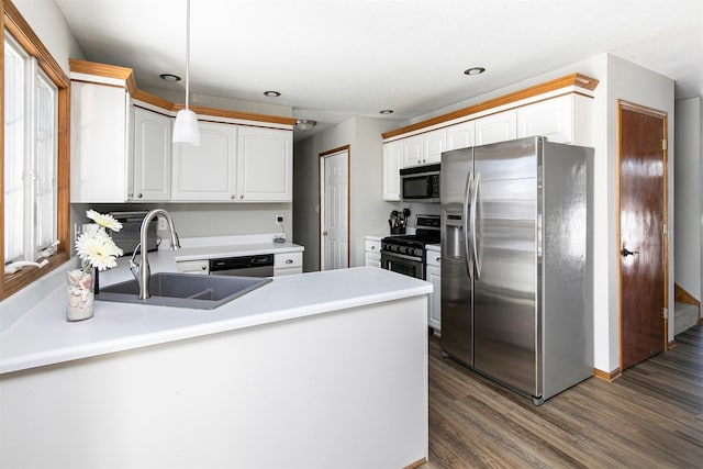 kitchen with a peninsula, dark wood-style flooring, a sink, hanging light fixtures, and appliances with stainless steel finishes