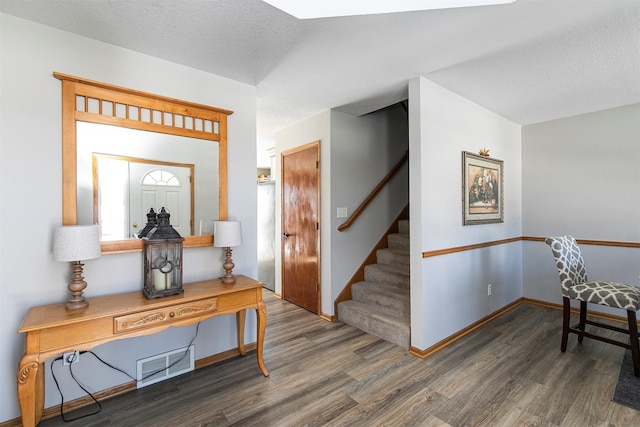 interior space with visible vents, stairway, a textured ceiling, wood finished floors, and baseboards