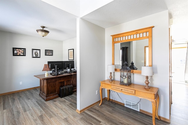 office area with a textured ceiling, baseboards, and wood finished floors