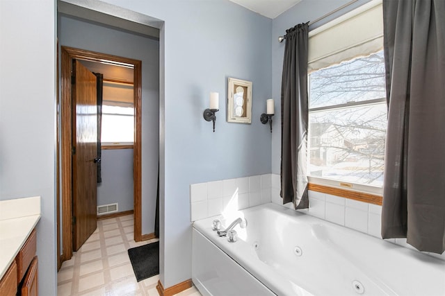 full bathroom featuring visible vents, a jetted tub, vanity, and tile patterned floors