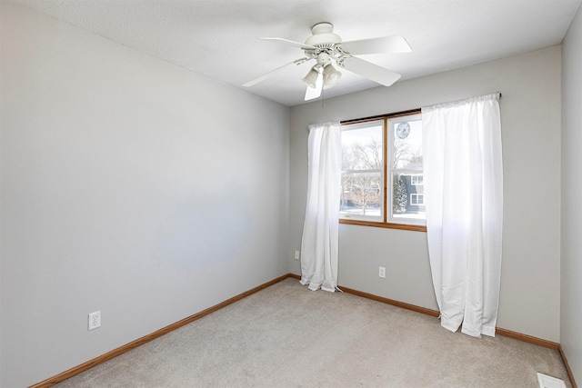 empty room with light carpet, visible vents, baseboards, and a ceiling fan