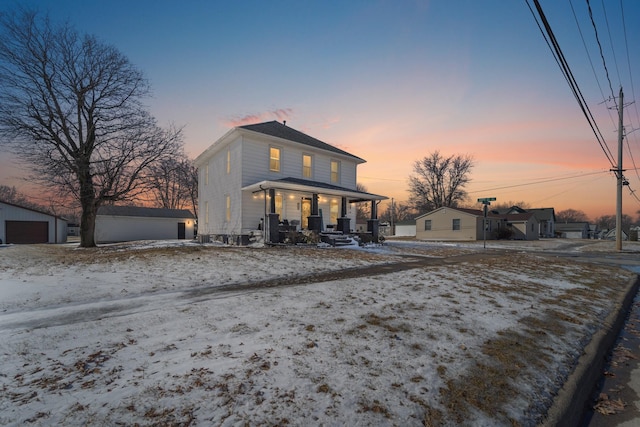 view of front of home with covered porch, a detached garage, and an outbuilding