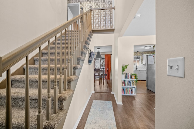 foyer entrance with stairs, a high ceiling, baseboards, and wood finished floors