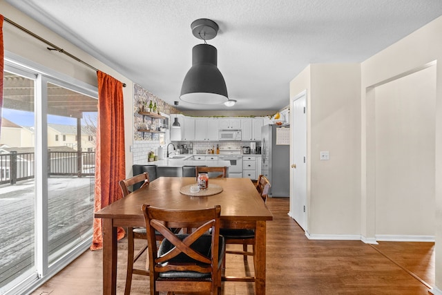 dining space with a textured ceiling, light wood-type flooring, and baseboards