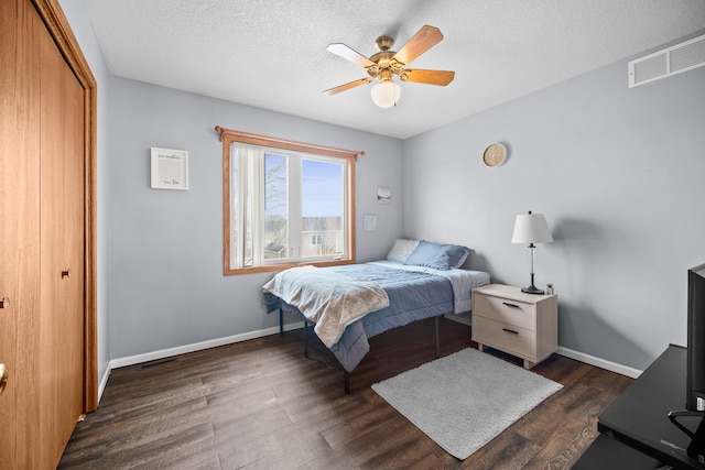 bedroom featuring a textured ceiling, dark wood-type flooring, visible vents, baseboards, and a closet