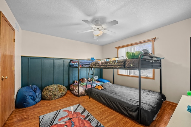 bedroom featuring ceiling fan, a textured ceiling, and wood finished floors