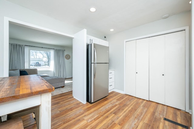 kitchen with open floor plan, freestanding refrigerator, light wood-style floors, wooden counters, and recessed lighting