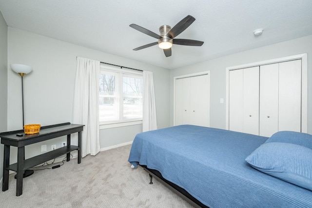 bedroom with multiple closets, light colored carpet, baseboards, and a ceiling fan