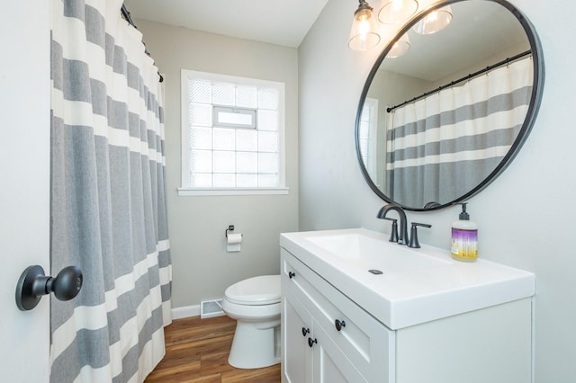 bathroom featuring visible vents, baseboards, toilet, wood finished floors, and vanity