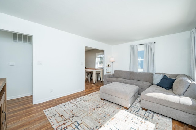 living room featuring baseboards, visible vents, and wood finished floors