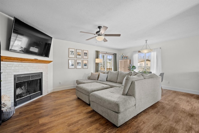 living room featuring a textured ceiling, a fireplace, wood finished floors, and a ceiling fan