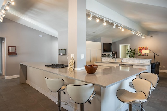 kitchen with lofted ceiling, a peninsula, light countertops, white cabinetry, and a sink