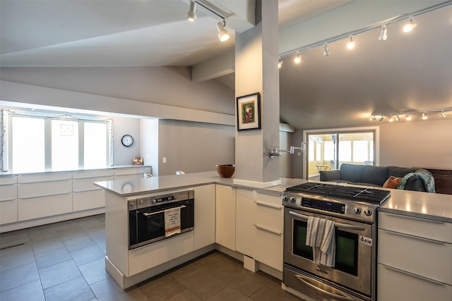 kitchen with stainless steel appliances, light countertops, open floor plan, vaulted ceiling, and a peninsula