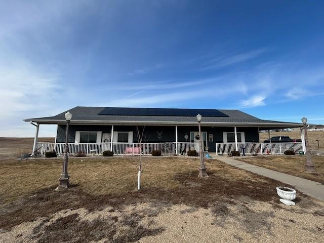 view of front facade featuring a porch and roof mounted solar panels