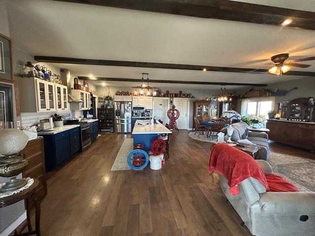 interior space featuring ceiling fan with notable chandelier, dark wood finished floors, and beam ceiling