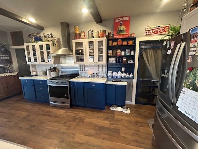 kitchen with dark wood-style floors, wall chimney range hood, stainless steel appliances, blue cabinetry, and backsplash