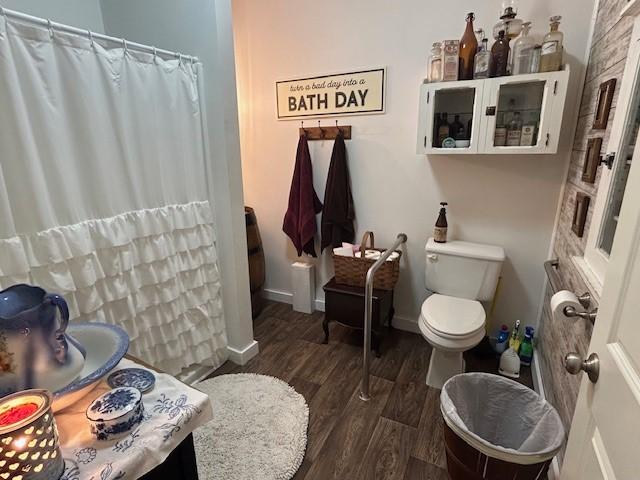 bathroom with toilet, baseboards, wood finished floors, and a shower with shower curtain