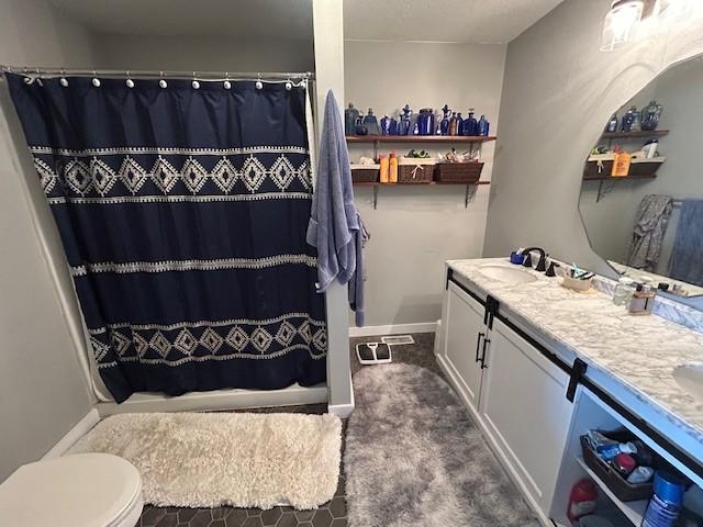 bathroom with double vanity, curtained shower, baseboards, and a sink