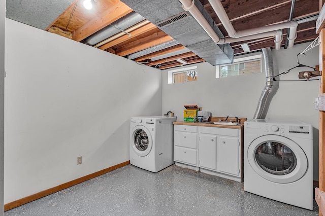 washroom featuring a sink, visible vents, baseboards, cabinet space, and washer and clothes dryer