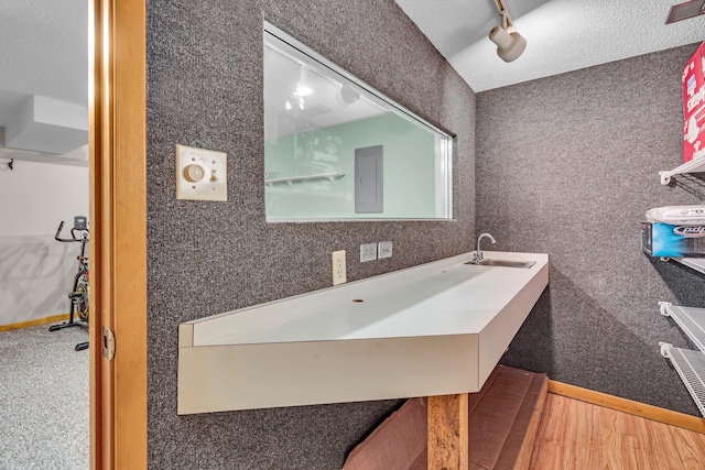 bathroom featuring a sink, a textured ceiling, baseboards, and wood finished floors