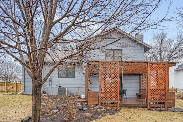 rear view of property with central AC unit, fence, a yard, a pergola, and a chimney