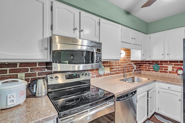 kitchen featuring stainless steel appliances, light countertops, a sink, and white cabinetry