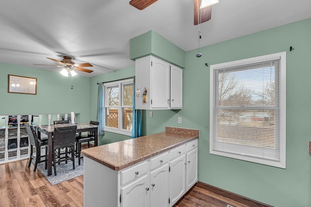 kitchen with light wood-style flooring, white cabinetry, and a ceiling fan