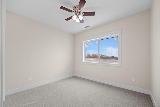 carpeted empty room with baseboards, visible vents, and ceiling fan